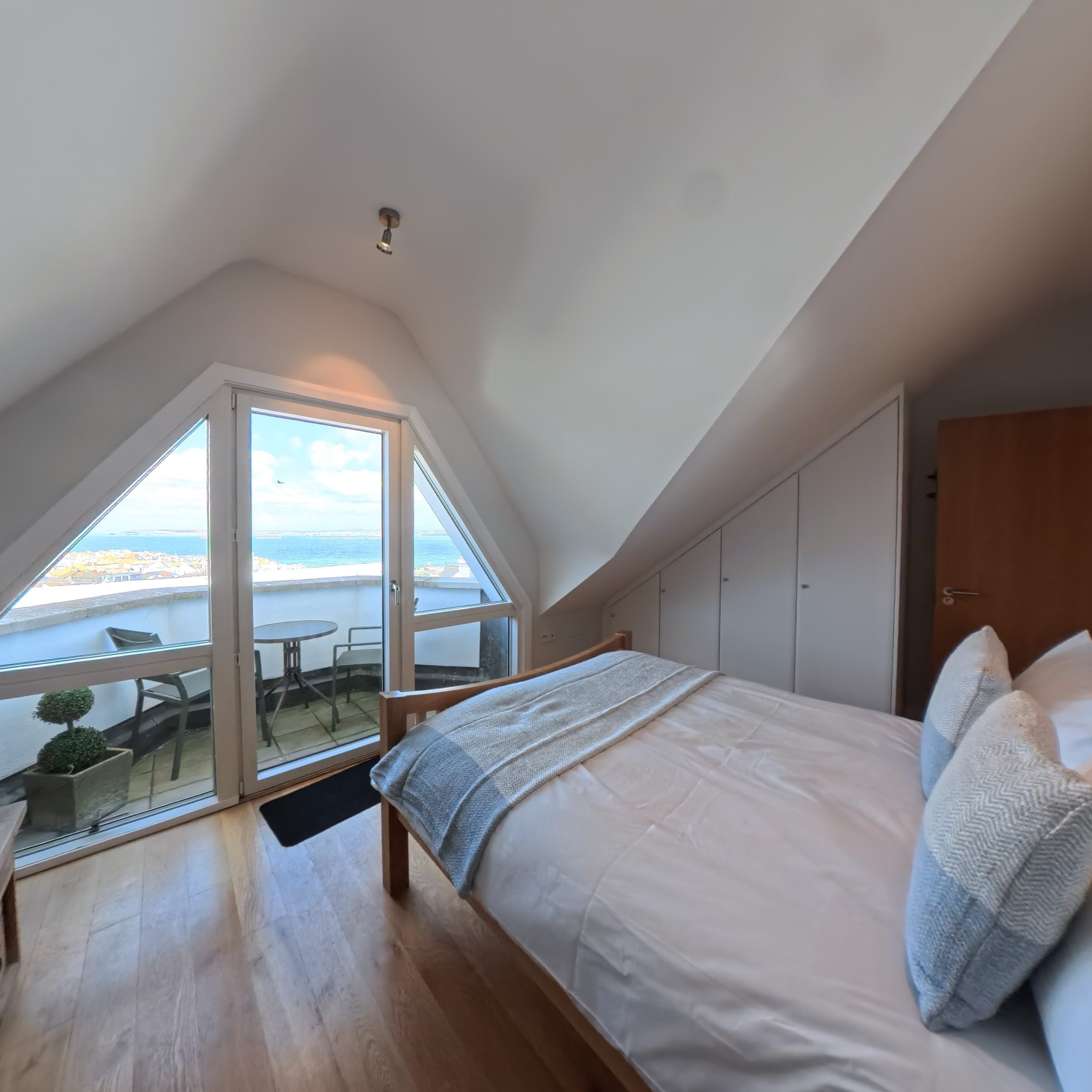 The bedroom at Tate Five, with the apex window and balcony doors framing the bay.