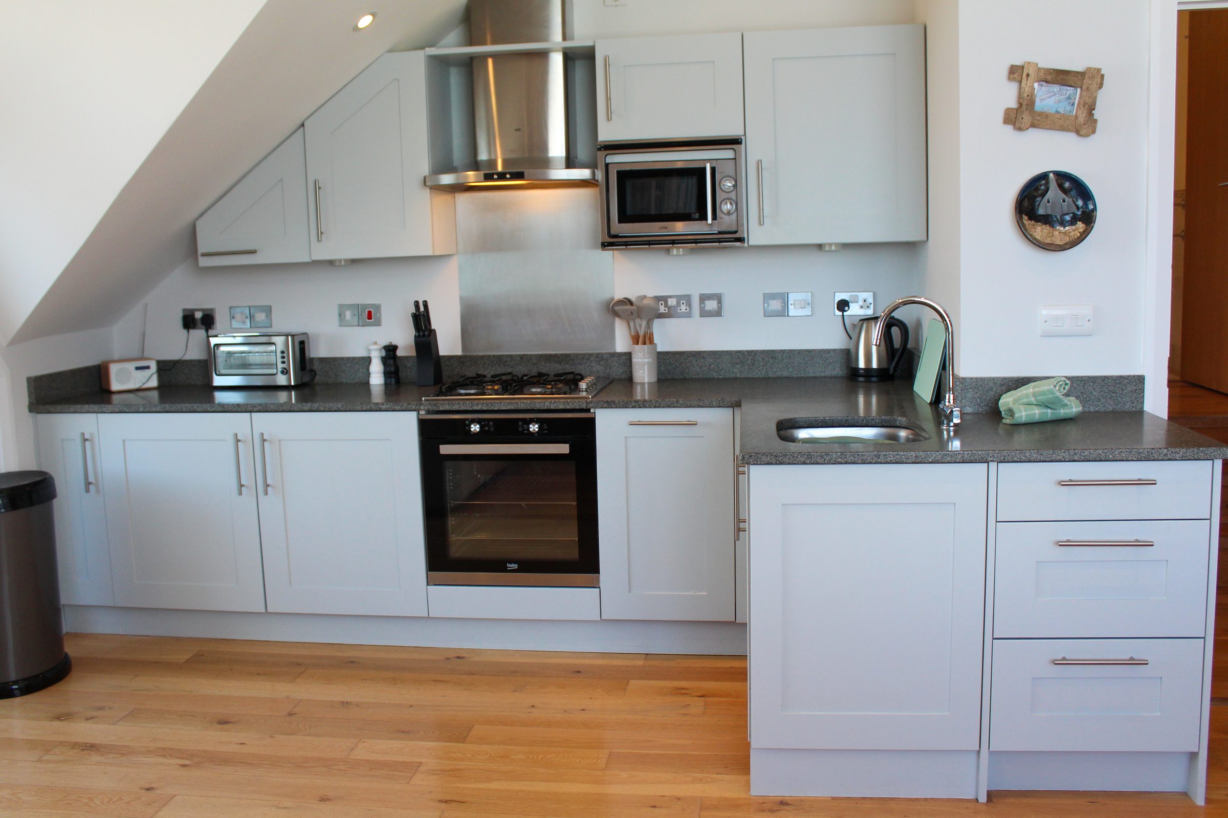 The kitchen at Tate Five, with pale grey cabinetry, gas hob and full oven tucked under the sloped ceiling.